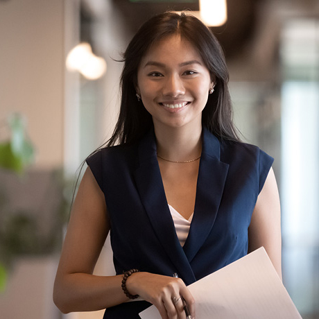 Woman standing in hallway holding pen and paper.