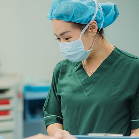 Woman wearing medical scrub, mask and hair cover.