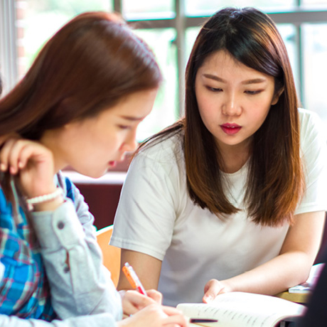 Women reading book in classroom.